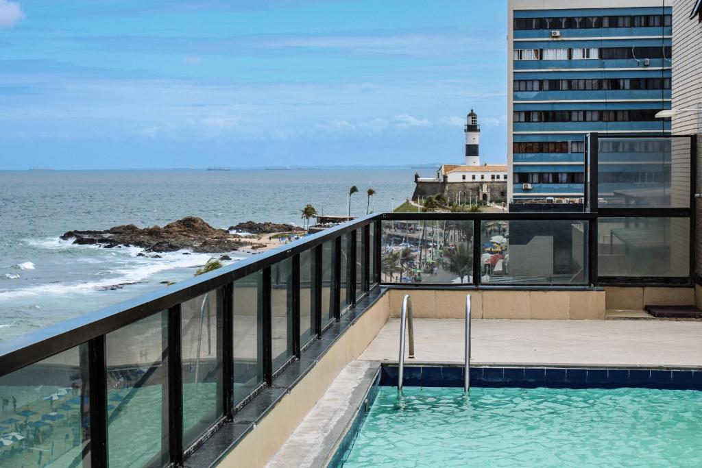 a swimming pool on the balcony of a building with a lighthouse at Apartamento Farol Barra Flat in Salvador