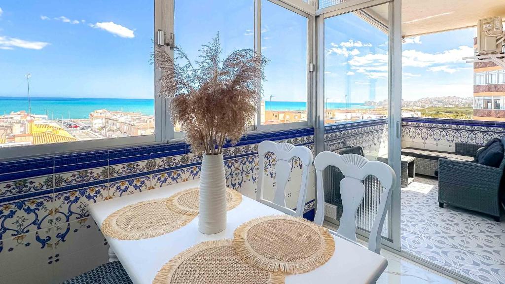 a table and chairs with a vase on top of a balcony at Sea View La Mata Apartment in La Mata