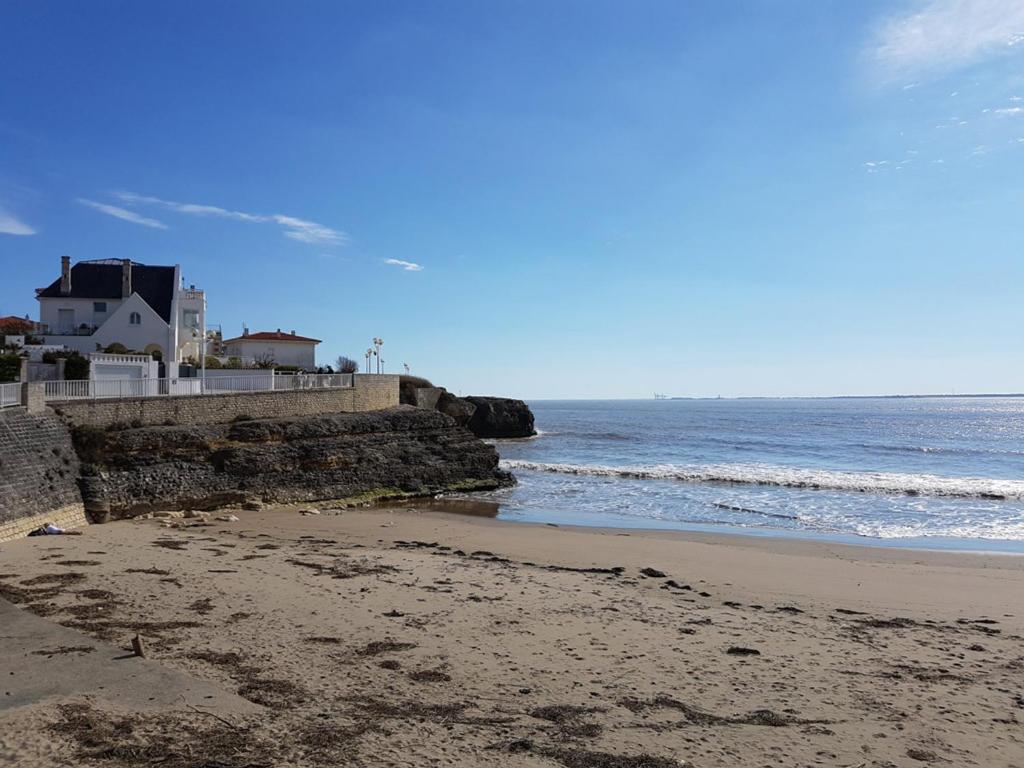 - une plage avec un bâtiment et l'océan dans l'établissement Maison authentique 6 pers, plage du Pigeonnier, Royan - FR-1-550-87, à Royan