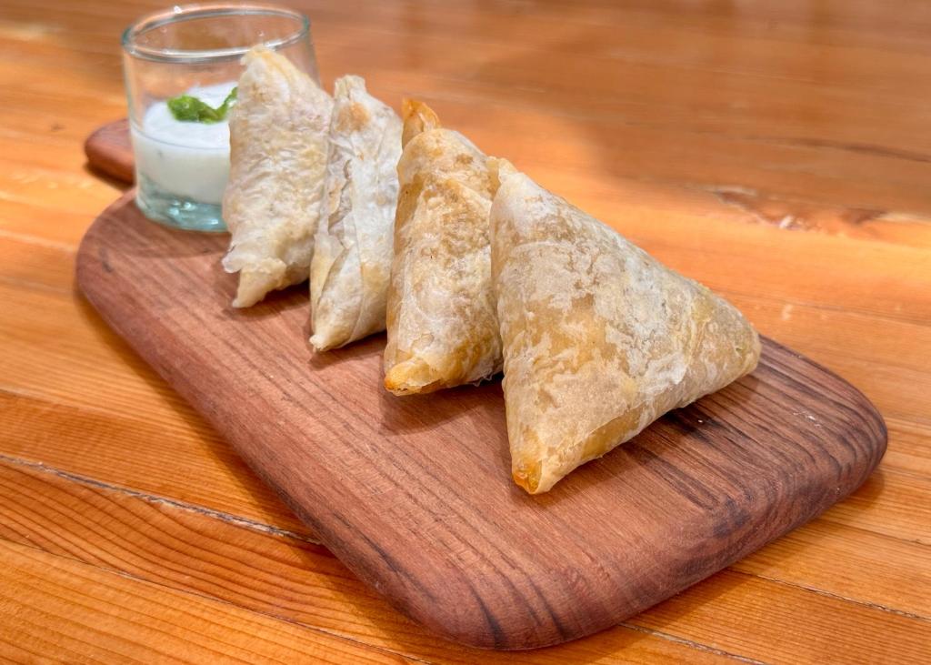 a wooden cutting board with four pieces of food at Hotel Al Alba Hammam & Restaurant in Asilah