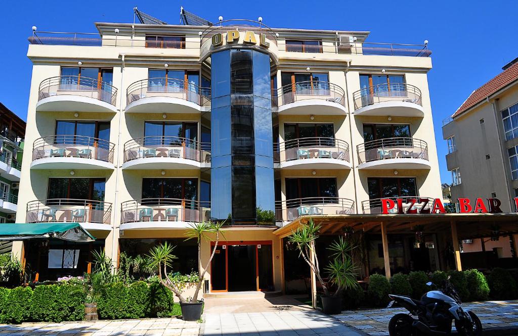 ein großes Gebäude mit Balkonen und einem Motorrad, das davor geparkt ist in der Unterkunft Hotel Opal in Primorsko