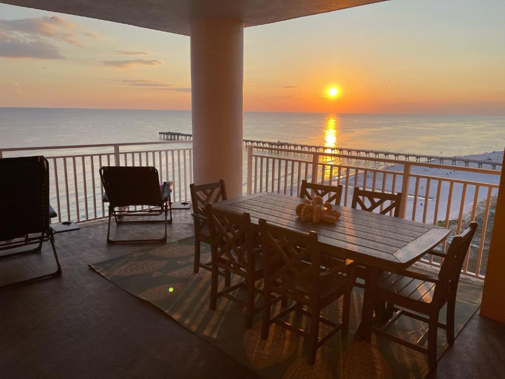 a table and chairs on a balcony with a sunset at Sterling Reef 907 - Brent's Beach in Panama City Beach