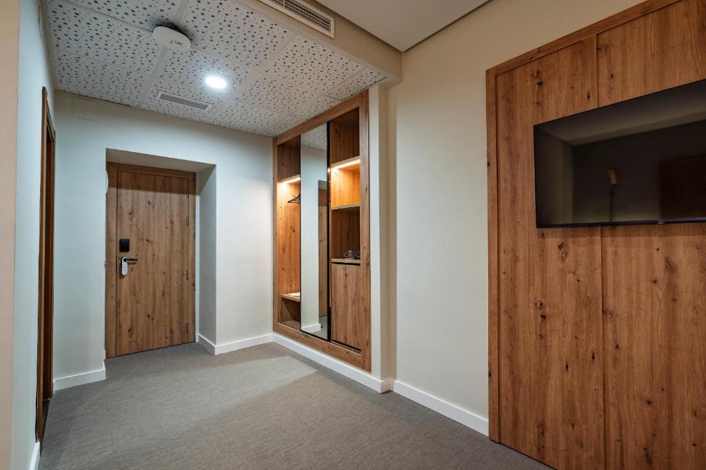 pasillo con TV de pantalla plana y puerta en Hotel Valle del Ambroz, en Hervás