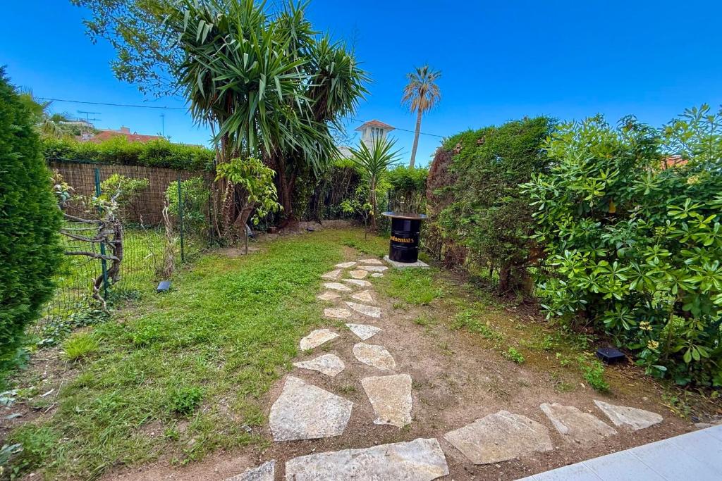 un chemin avec une poubelle au milieu d'une cour dans l'établissement Golfe-Juan 4 People Garden & Garage, au Golfe-Juan