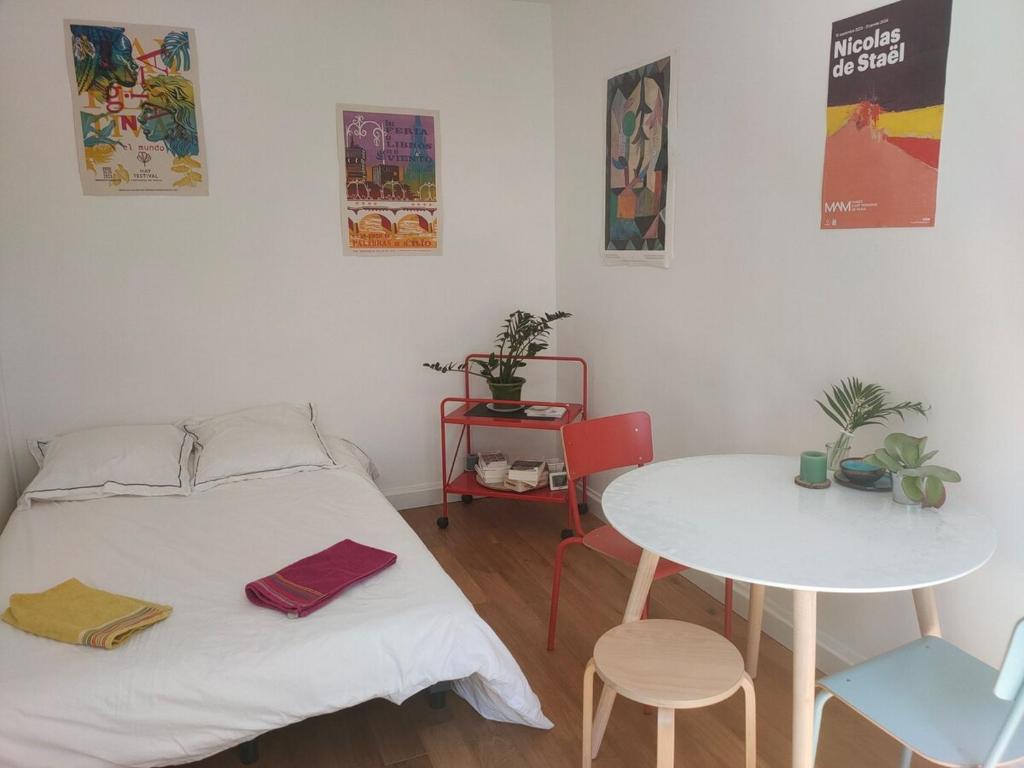 une petite chambre avec un lit et une table dans l'établissement Charmant studio au calme, à Paris