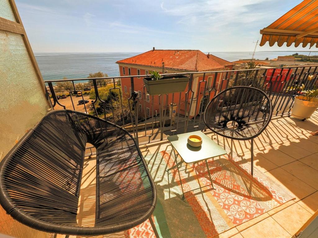 Un balcón con dos sillas y una mesa con vista al mar. en Appartement familial - Vue mer, en Bastia