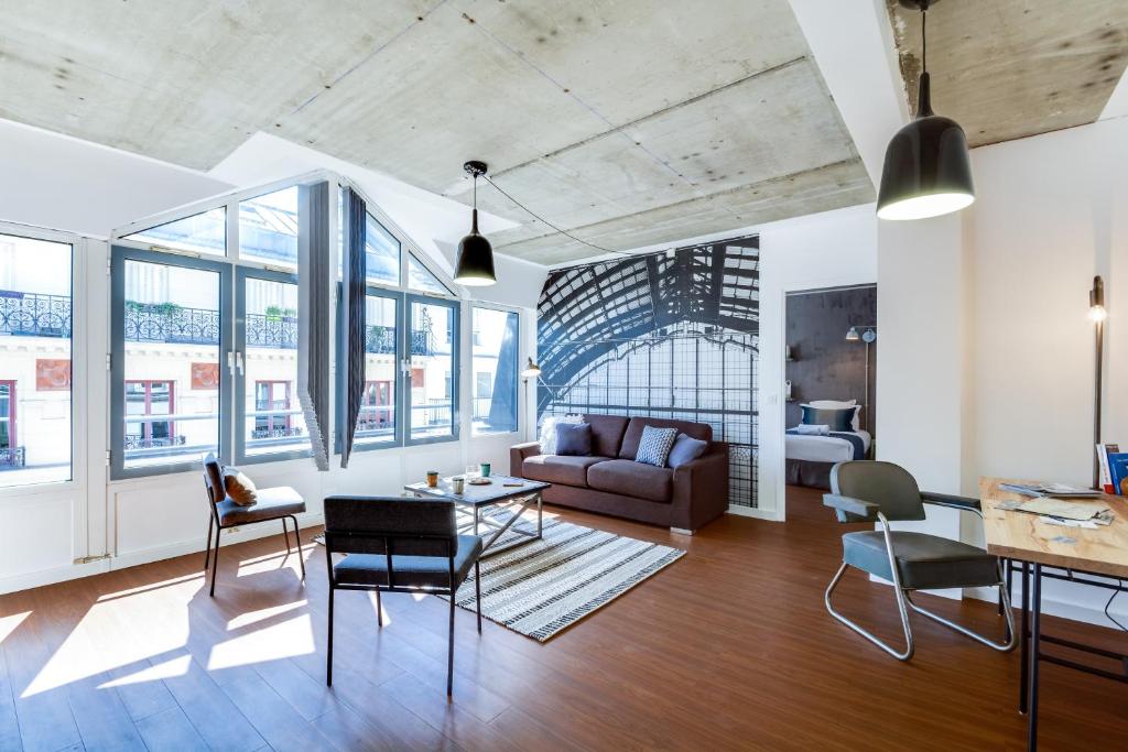 un salon avec un canapé, des chaises et des fenêtres dans l'établissement Sweett - La Roserie, à Paris