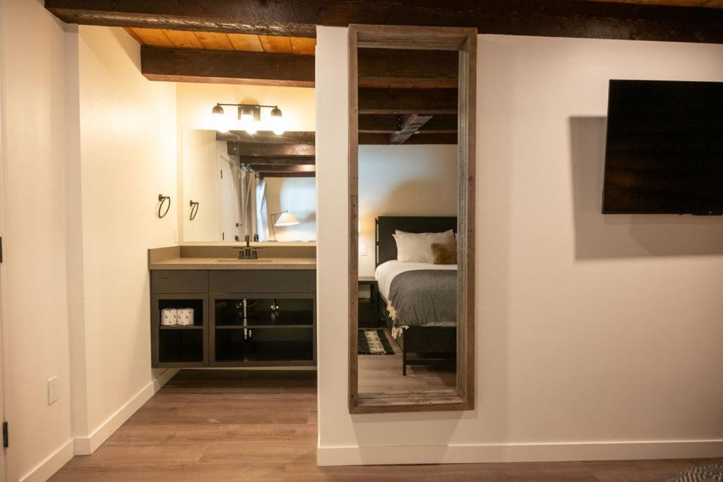 a mirror in a room with a bed and a sink at High Creek Lodge and Cabins in Pagosa Springs