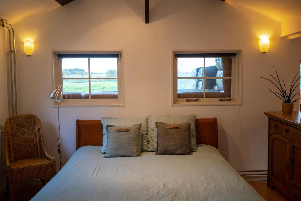 a bedroom with a white bed with two windows at Rancho Bejarano in Kollumerpomp