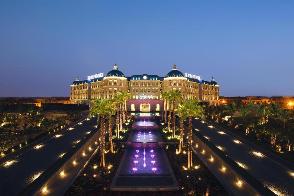 a building with palm trees and lights at night at Royal Maxim Palace Kempinski Cairo in Cairo