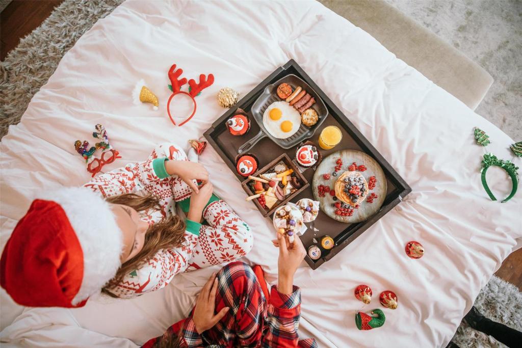 a girl in a santa hat laying on a bed with a tray of food at Royal Maxim Palace Kempinski Cairo in Cairo