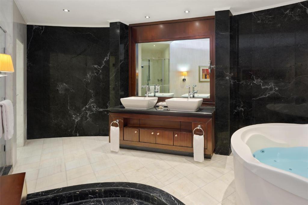a bathroom with two sinks and a tub and a mirror at Royal Maxim Palace Kempinski Cairo in Cairo