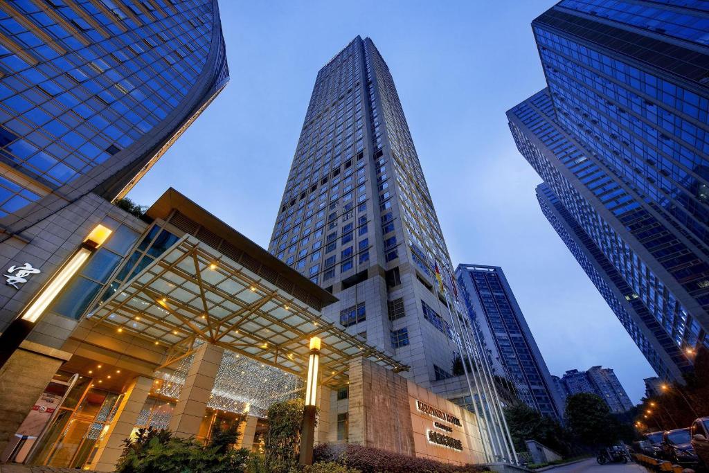 a tall building in a city with tall buildings at Kempinski Hotel Chongqing in Chongqing