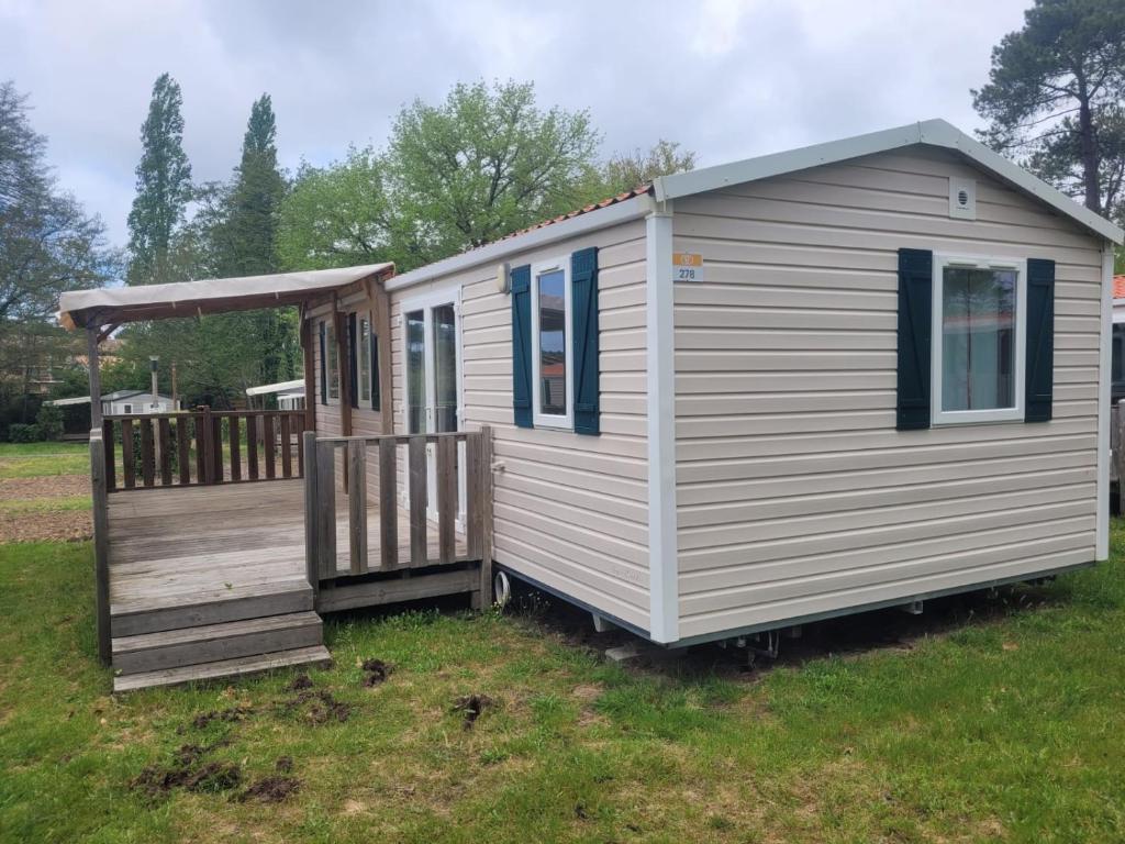 Une petite maison blanche avec une terrasse couverte dans un champ dans l'établissement mobil home, à Lit-et-Mixe