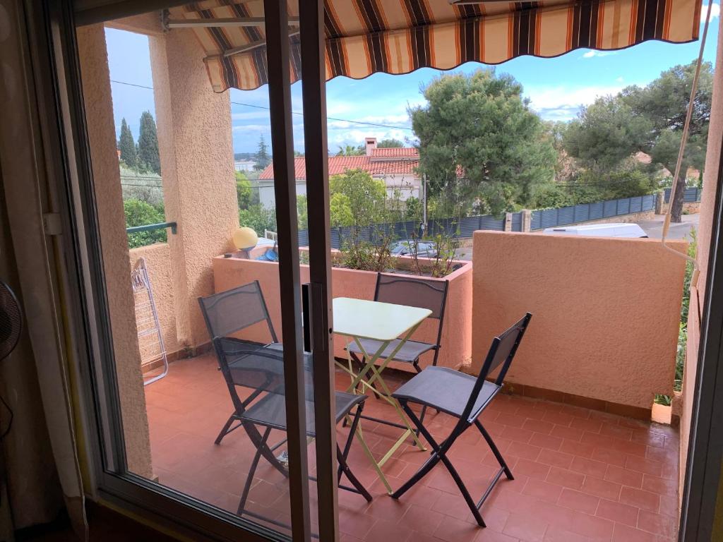 un patio avec deux chaises et une table sur un balcon dans l'établissement Appartement Bandol dans résidence privée avec piscine, à Bandol