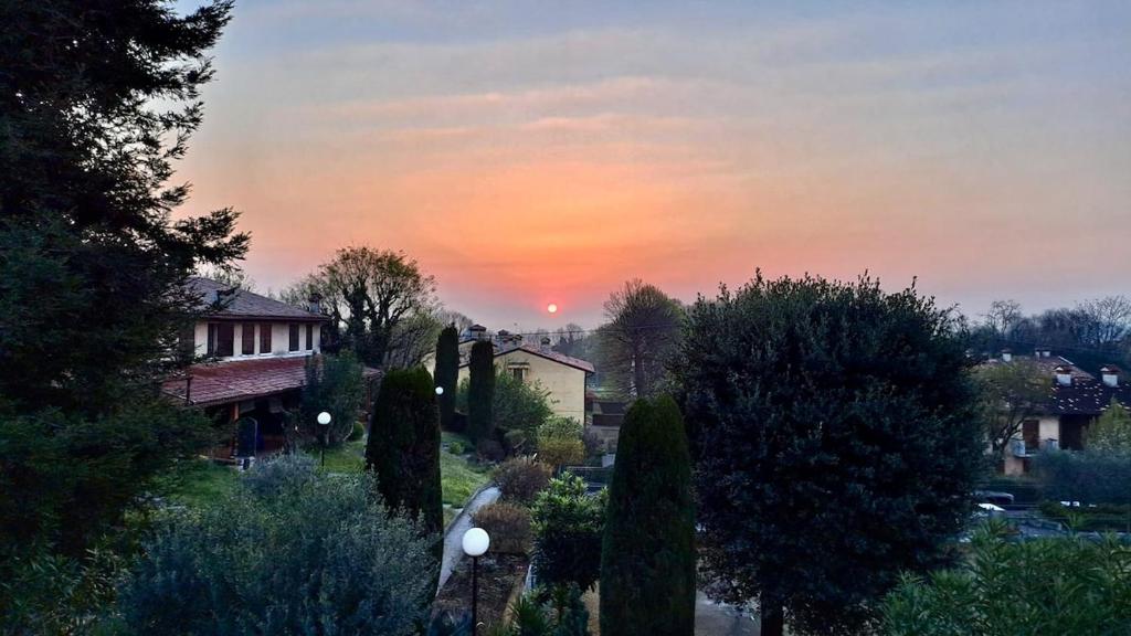 ポンティ・スル・ミンチョにあるL'Alba al Cascinale - by tourquoiseveaの木々や家々のある庭園に沈む夕日