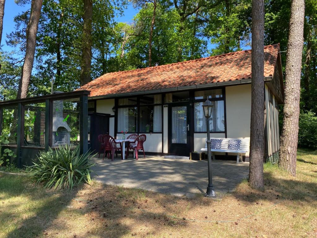 a house with a conservatory with a table and chairs at Huisje Buurserbeek in Haaksbergen