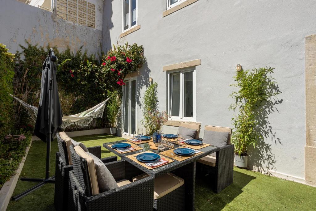 een buitentafel met stoelen en een parasol op het gras bij Charming and Cozy beach apartment in Estoril