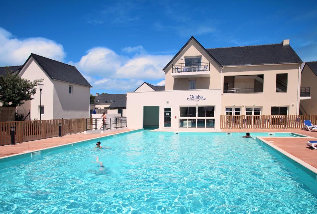 a swimming pool in front of a house at Résidence Odalys Les Iles du Morbihan in Baden