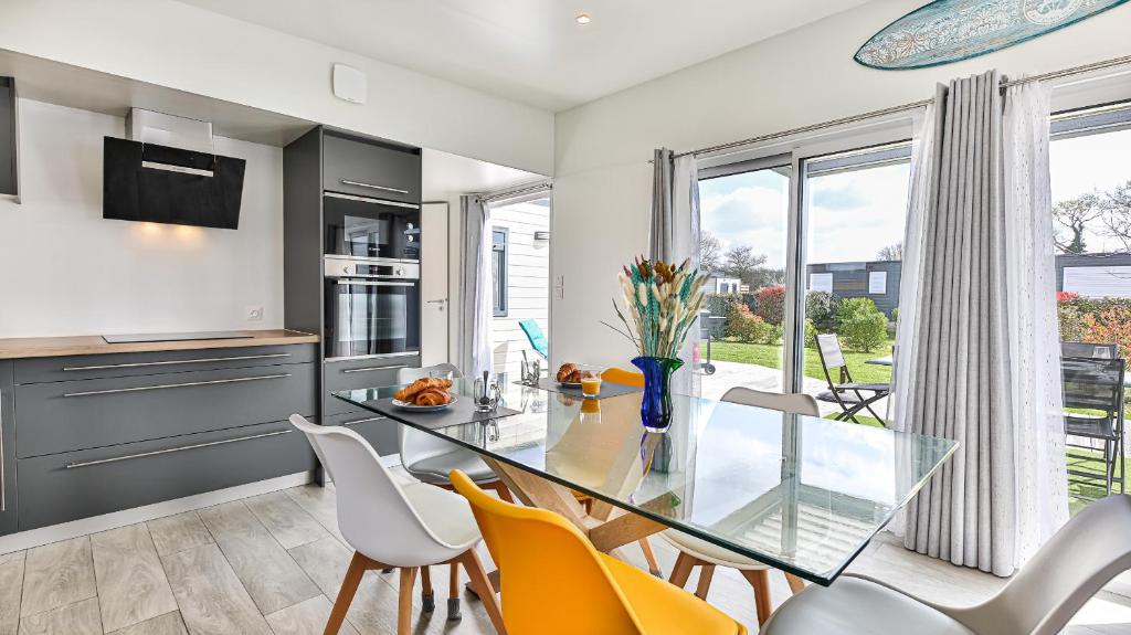 une cuisine et une salle à manger avec une table et des chaises en verre dans l'établissement LE FAMYLISSE Séjour d'Exception Confort & Bien-Être en Lodge familial - 10min des Sables d'Olonne, à Sainte-Foy