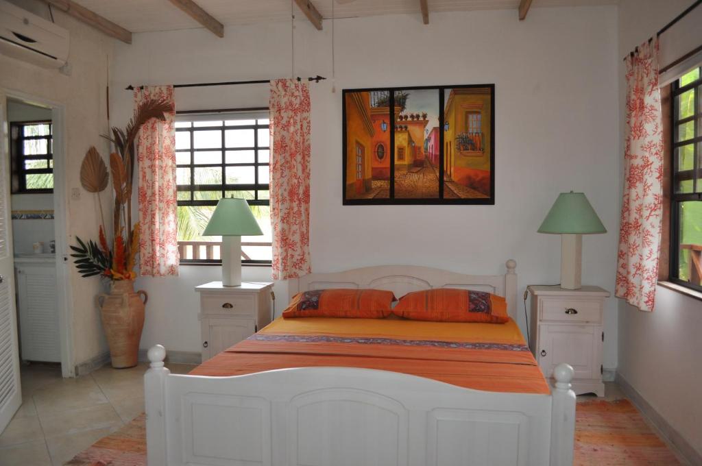 um quarto com uma cama branca e almofadas laranja em Yellow Bird Apartment em Christ Church