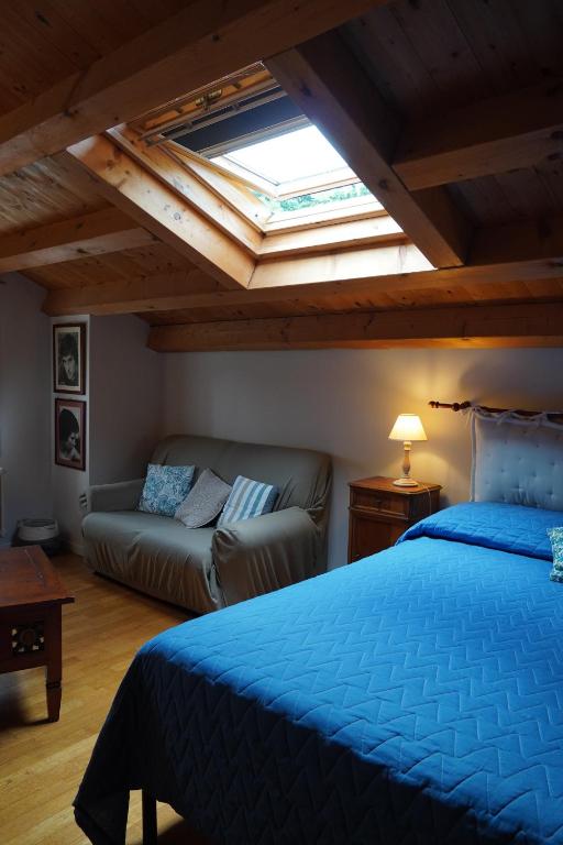 a bedroom with a blue bed and a couch at La Casa del Glicine Tarzo in Fratta