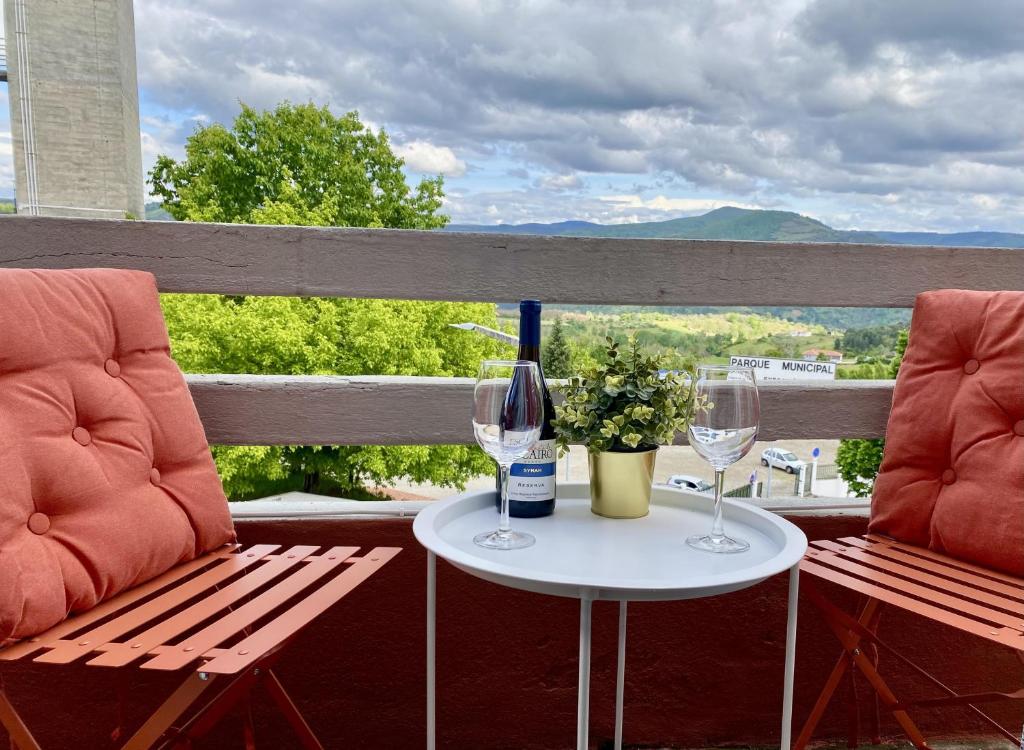 two chairs and a table with wine glasses on a balcony at Casa dos Frades in Vinhais
