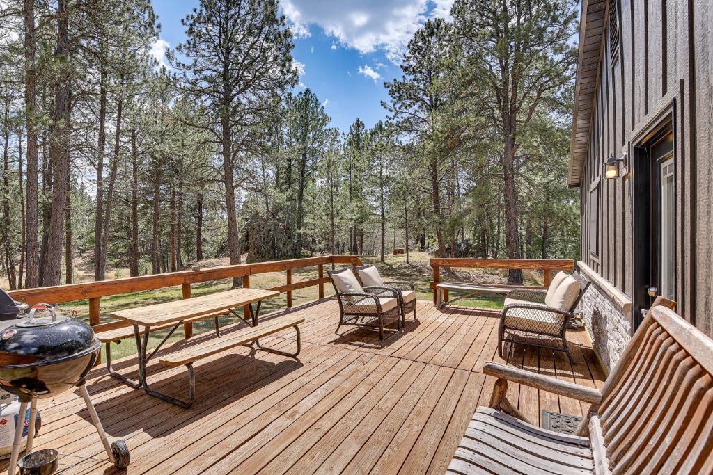 a wooden deck with benches and a table and chairs at Private Black Hills Home with Corral Horses Welcome in Custer