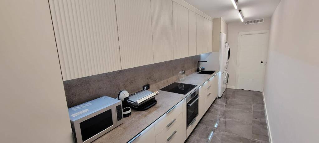 a kitchen with white cabinets and a sink and a microwave at Sol Del Mar in Benicarló