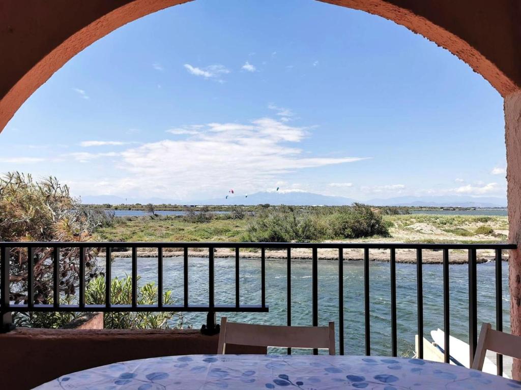 - un balcon avec une table et des chaises offrant une vue sur l'eau dans l'établissement Résidence Les Arcades 2 - STUDIO MEZZANINE 4 PERSONNES 4 couchages LE BARCARÈS. Réf: 9ARC2_136 MAE-8493, au Barcarès