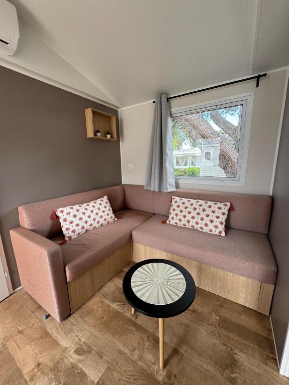 - un petit salon avec un canapé et une fenêtre dans l'établissement Mobile Home 146, 5 pers Camping Siblu 4 étoiles le Lac des Reves, à Lattes