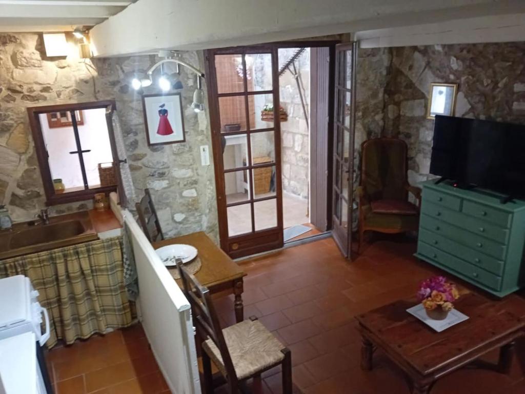 un salon avec une télévision et une table dans l'établissement Le refuge, à Arles