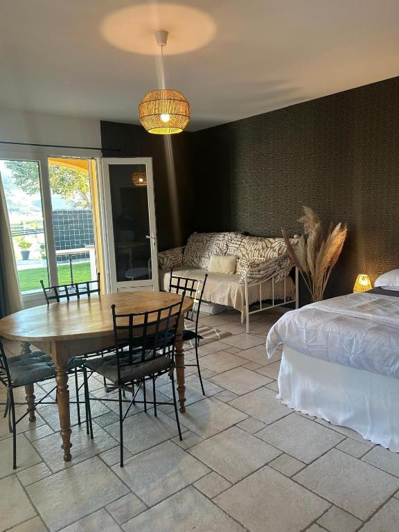 une chambre avec un lit, une table et des chaises dans l'établissement Appartement avec piscine et spa, à Privas