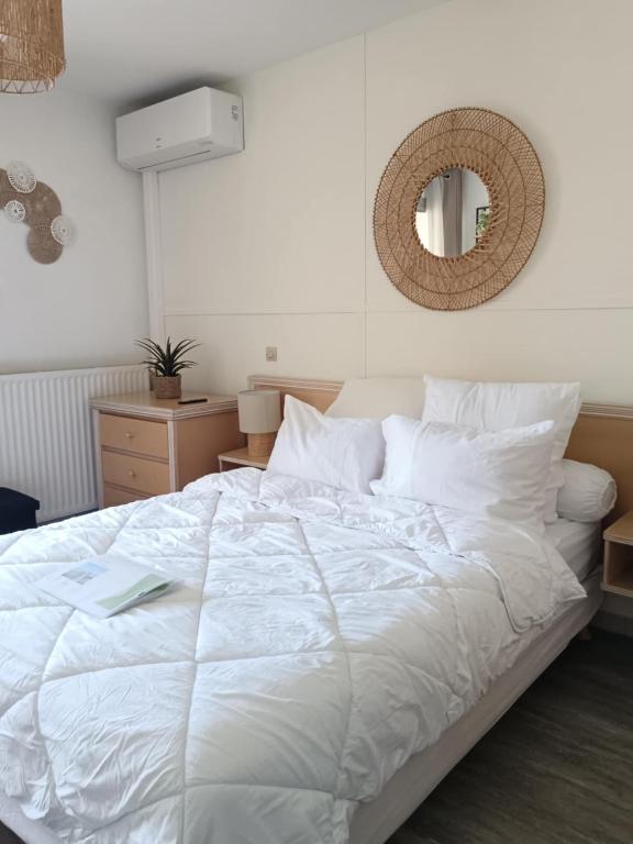 une chambre avec un lit blanc et un miroir dans l'établissement Agréable studio climatisé, avec parking, piscine et vue, à Balaruc-les-Bains