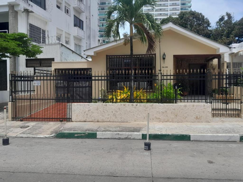 a building with a black fence and a palm tree at Casa Estela in Cartagena de Indias