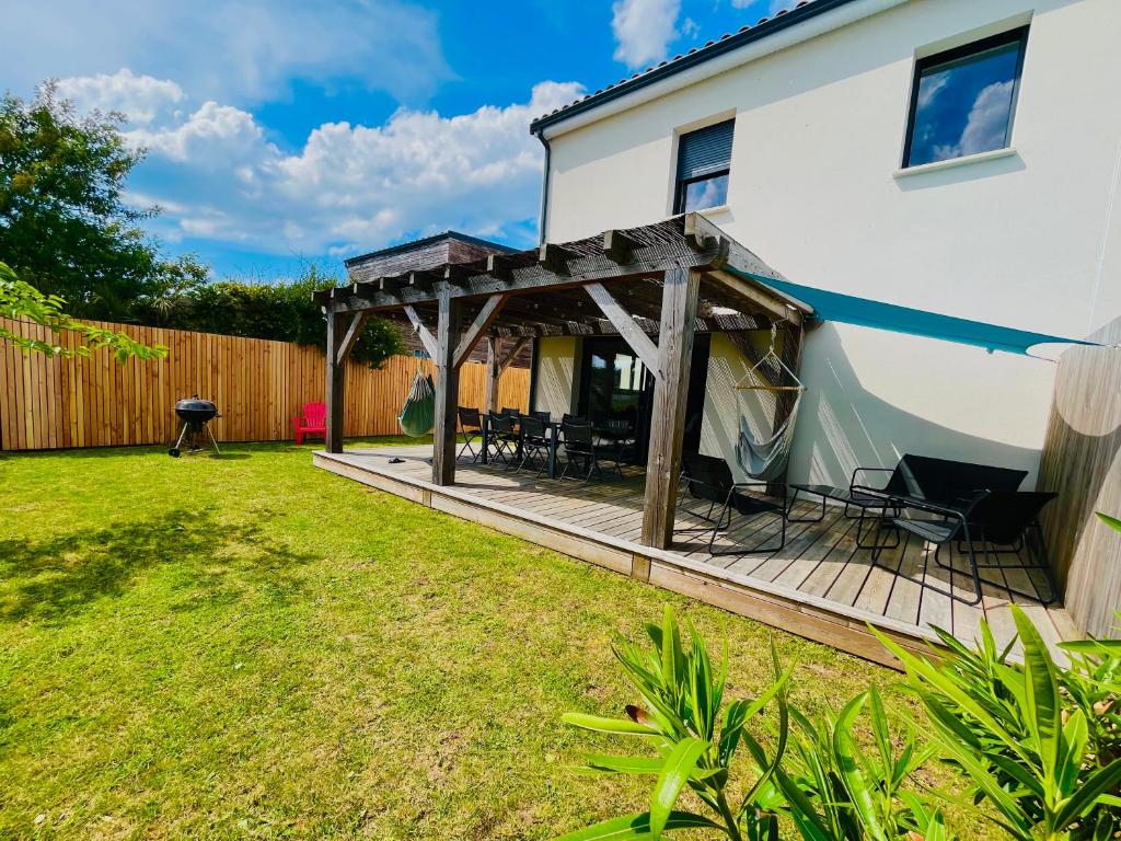 une cour arrière avec une terrasse en bois avec des chaises et des tables dans l'établissement Entre plage et détente aux Conches, Maison avec terrasse et jardin privé, à Longeville-sur-Mer