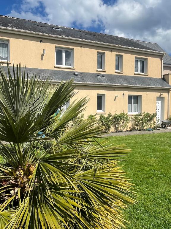 un grand bâtiment avec un palmier devant dans l'établissement Gites de la Mouette Le Bigorneau nid cotier 2 personnes, à Ravenoville