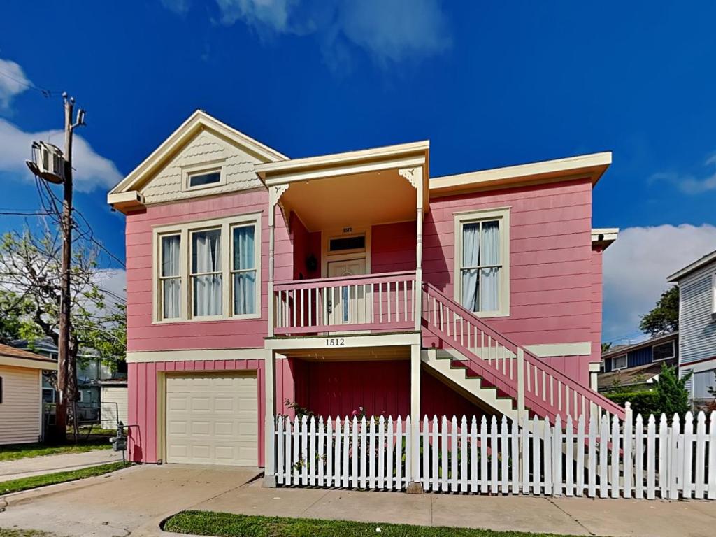 una casa rosa con una recinzione bianca davanti di The Vintage Sea Turtle a Galveston