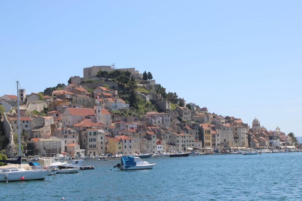 un groupe de bateaux dans l'eau devant une ville dans l'établissement Apartman Lavanda, à Šibenik