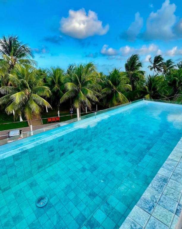 a swimming pool with palm trees in the background at Patacho Brisa Mar - Triplex na Rota Ecológica dos Milagres in Pôrto de Pedras