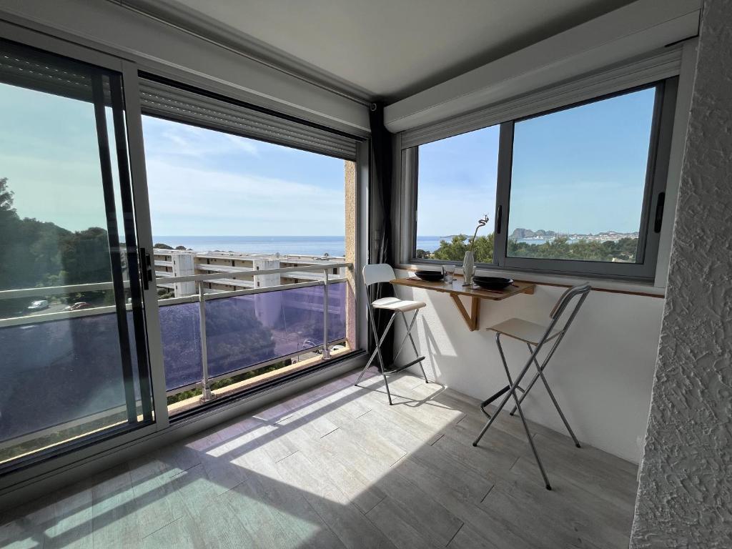 Cette chambre dispose de grandes fenêtres et d'un bureau avec vue. dans l'établissement Clap de Soleil Studio Vue Mer, Clim, Fibre, Idéal 2 Pers, à La Ciotat