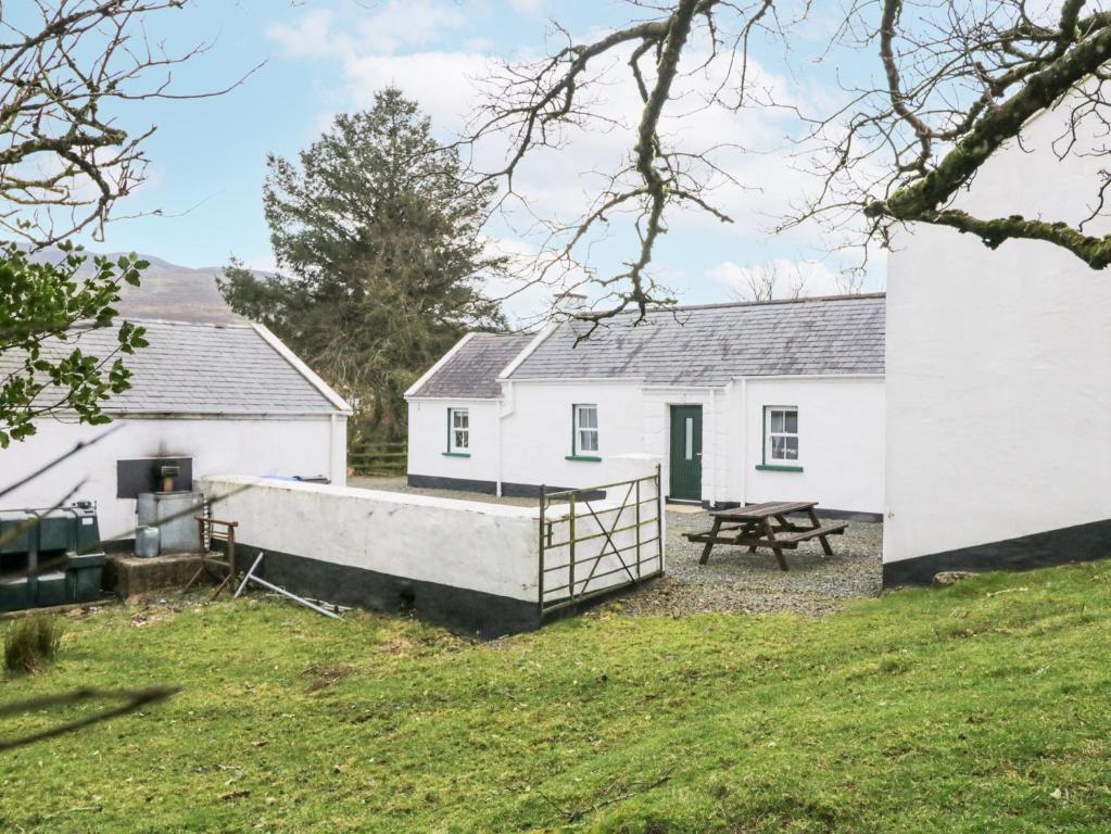 a white house with a picnic table in front of it at Ballard Cottage Annexe in Newry