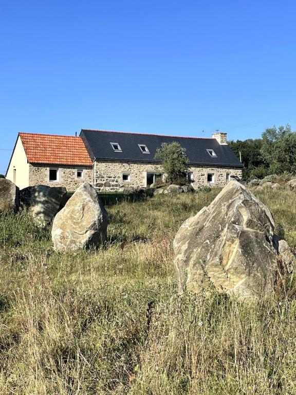 a house in a field with rocks in front of it at Menhirs et Moutons Ouessant in Plouëc-du-Trieux