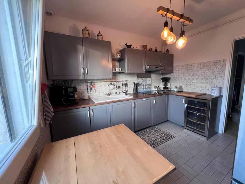 une cuisine avec des placards gris et une table en bois dans l'établissement Lna, à La Celle-sous-Gouzon