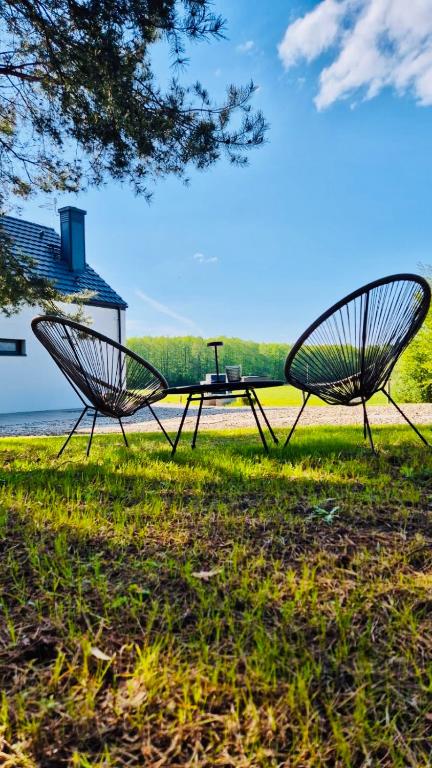 two metal chairs sitting in the grass with a table at Strefa Natur dom z jacuzzi na wyłączność in Matyty
