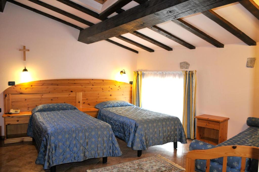 a bedroom with two beds and a cross on the wall at Hotel Vittoria in Riva del Garda