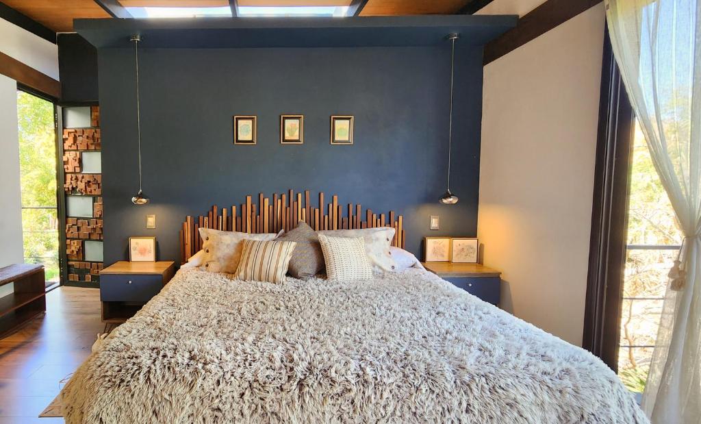 a bedroom with a large bed with a blue wall at Garden Suite in Valle de Bravo