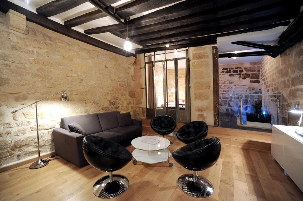ein Wohnzimmer mit einem Sofa und schwarzen Stühlen in der Unterkunft Apart of Paris - Souplex Loft Apartment - Le Marais in Paris