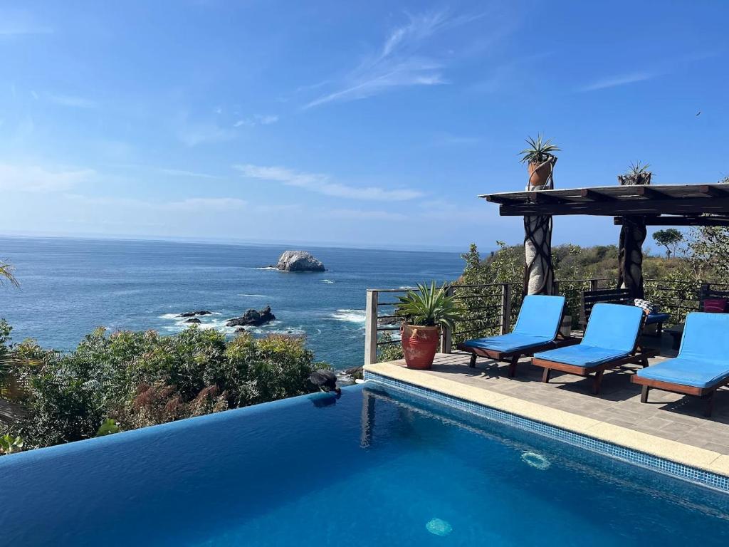 a swimming pool with chairs and a view of the ocean at Casa Kalmar in Zipolite