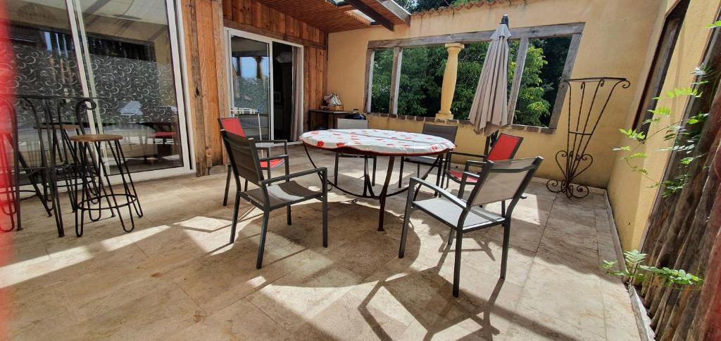 un patio avec une table, des chaises et un parasol dans l'établissement Residence Pinta Sarlat, à Sarlat-la-Canéda